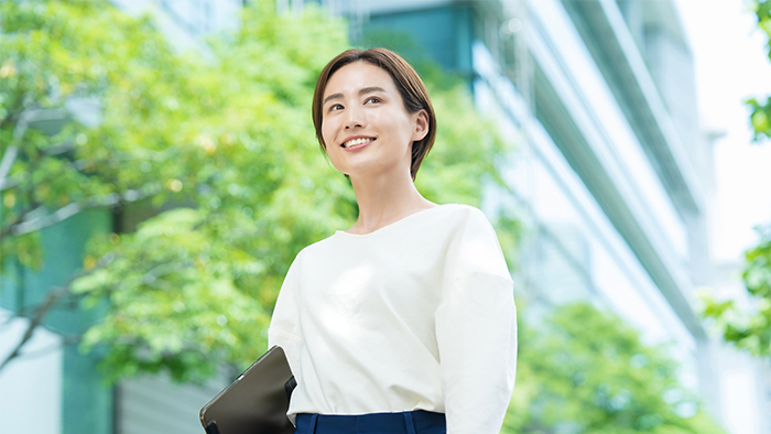 オフィス街に立つ笑顔の女性